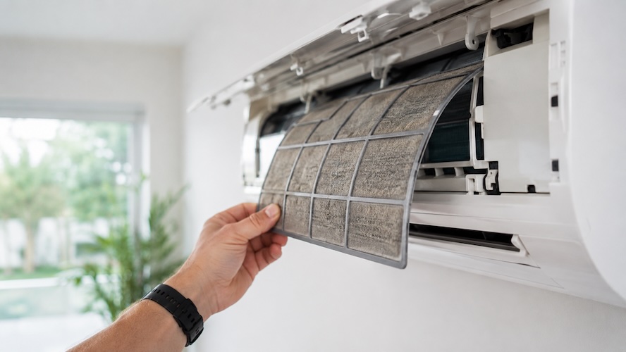 hand taking dirty split system filter out of ac